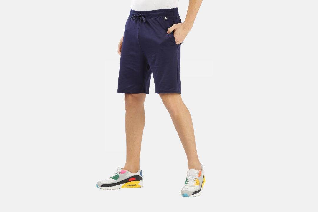 Man wearing navy blue shorts and sneakers demonstrating how to choose the perfect summer shorts