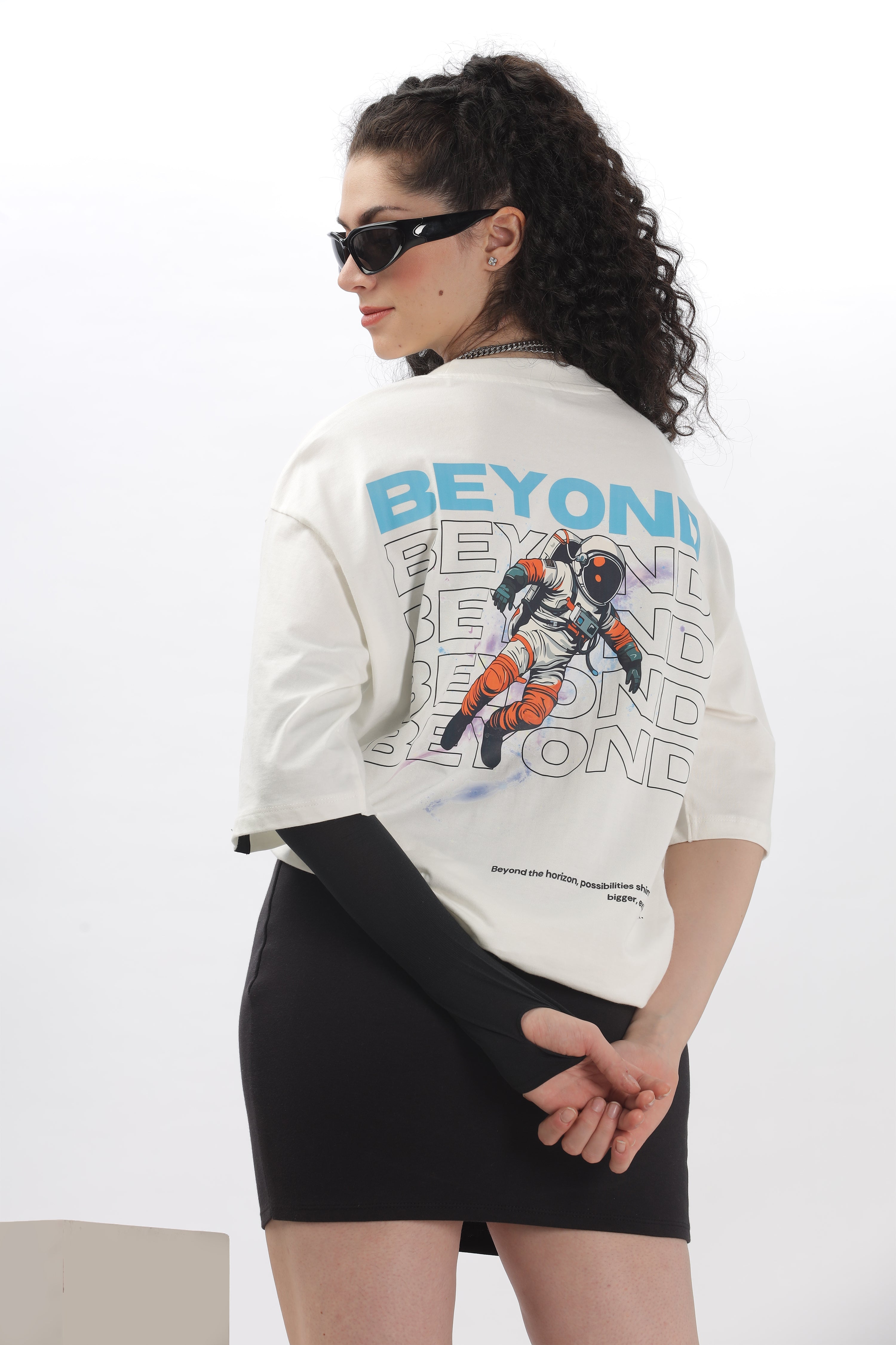 Woman wearing a printed oversized t shirt with astronaut graphic and text beyond on the back