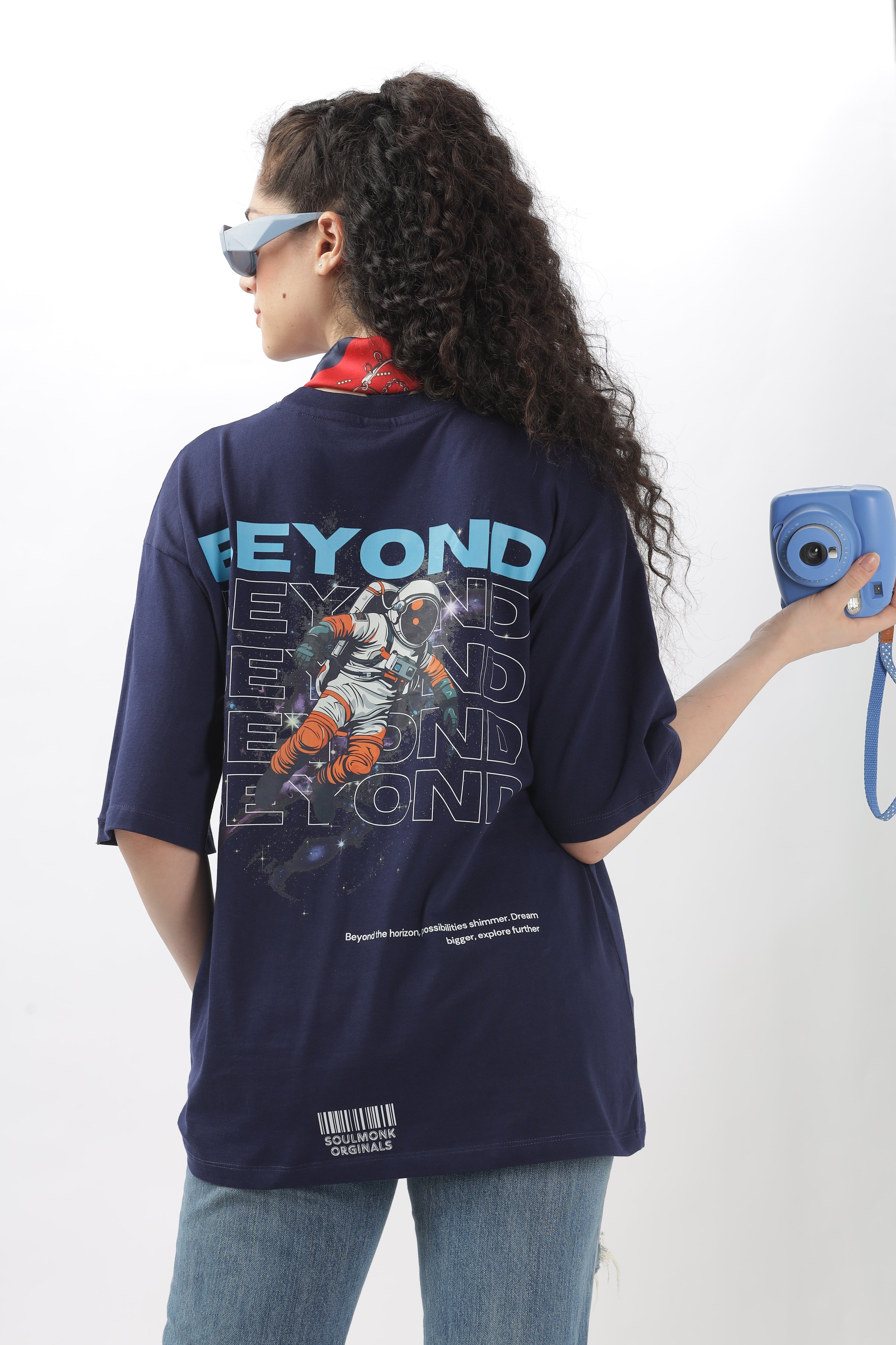 Woman wearing navy Beyond Oversized T-Shirt Collection Women with astronaut print on back and holding a blue camera