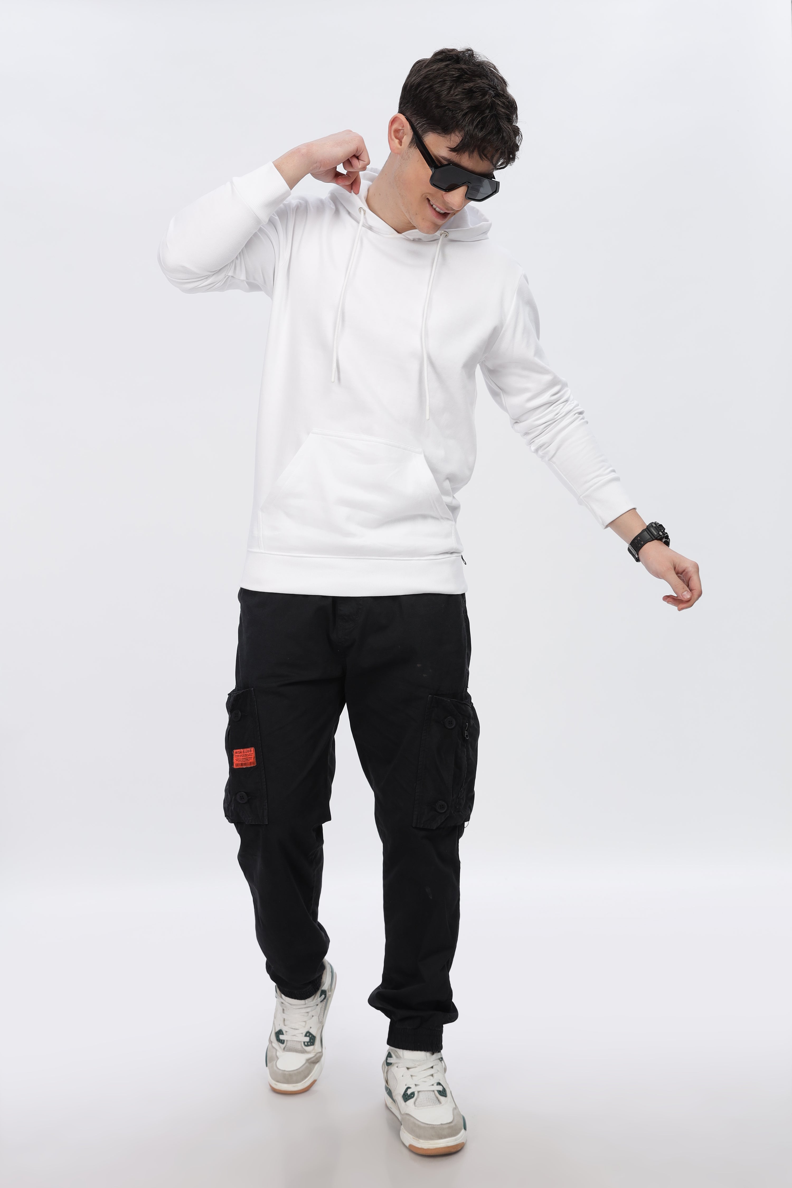 Young man wearing a frost white premium sibling hoodie paired with black cargo pants and sneakers