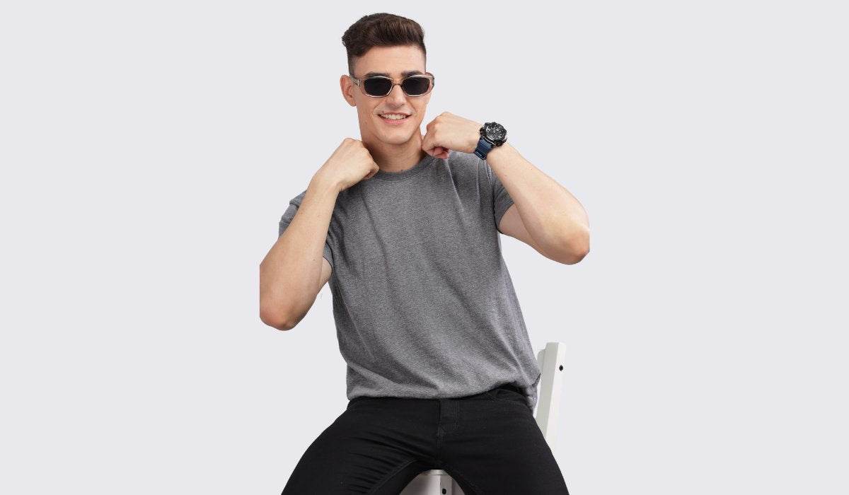 Man wearing a gray premium casual t shirts sitting on a chair with sunglasses and a watch