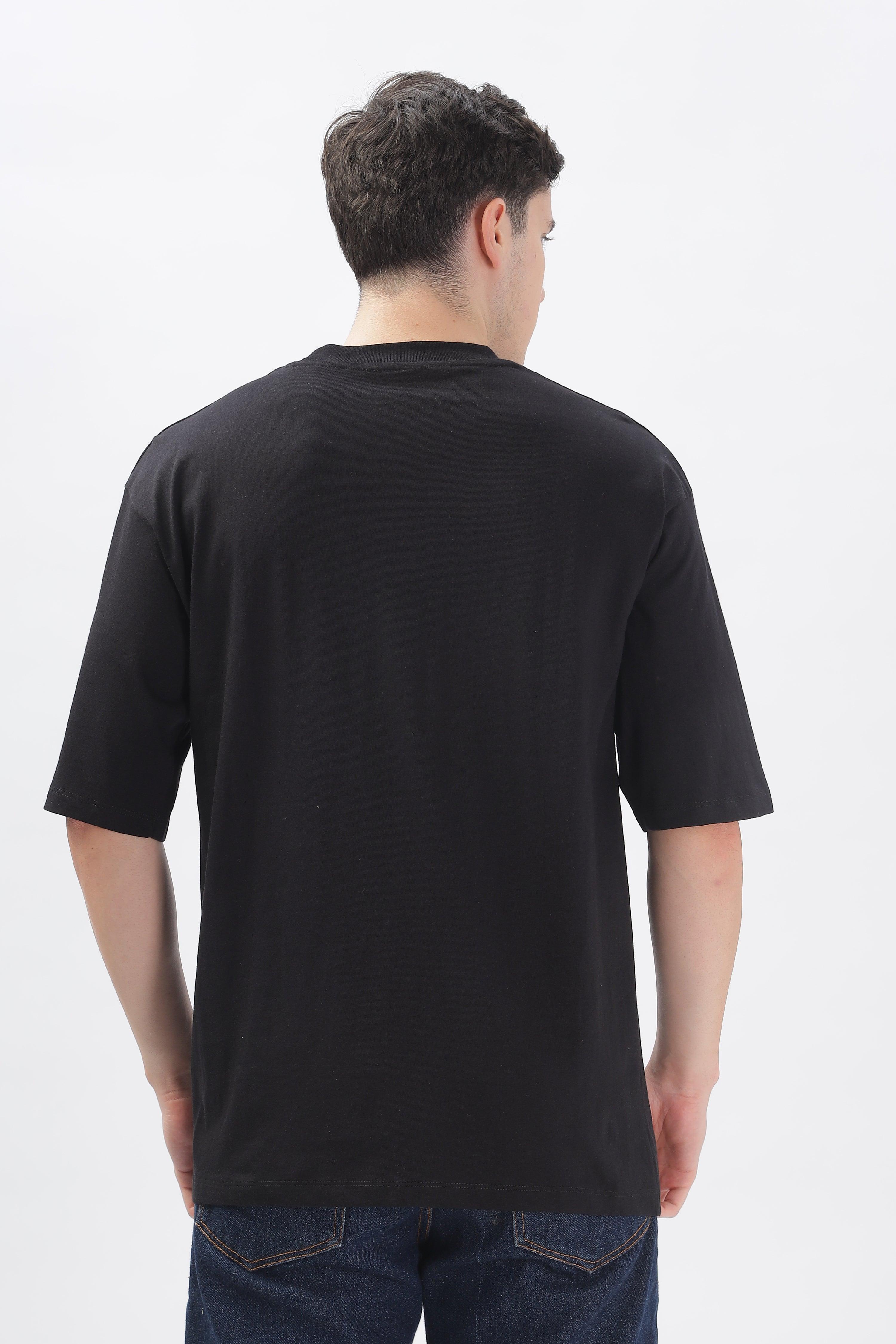 Back view of a male model wearing a black oversized t-shirt for men paired with blue jeans