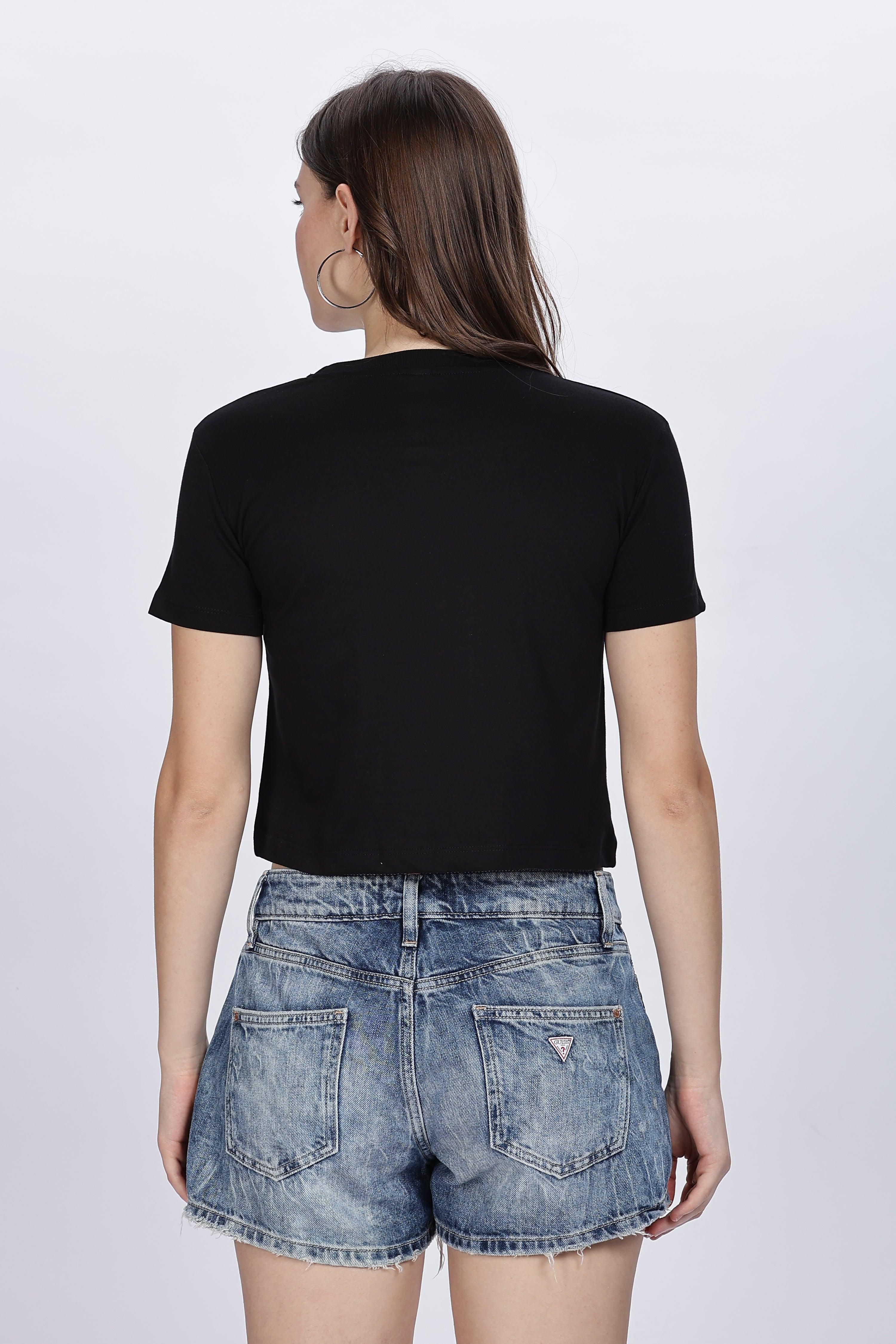 Woman wearing Soulmonk black solid crop top with short sleeves and denim shorts from back view