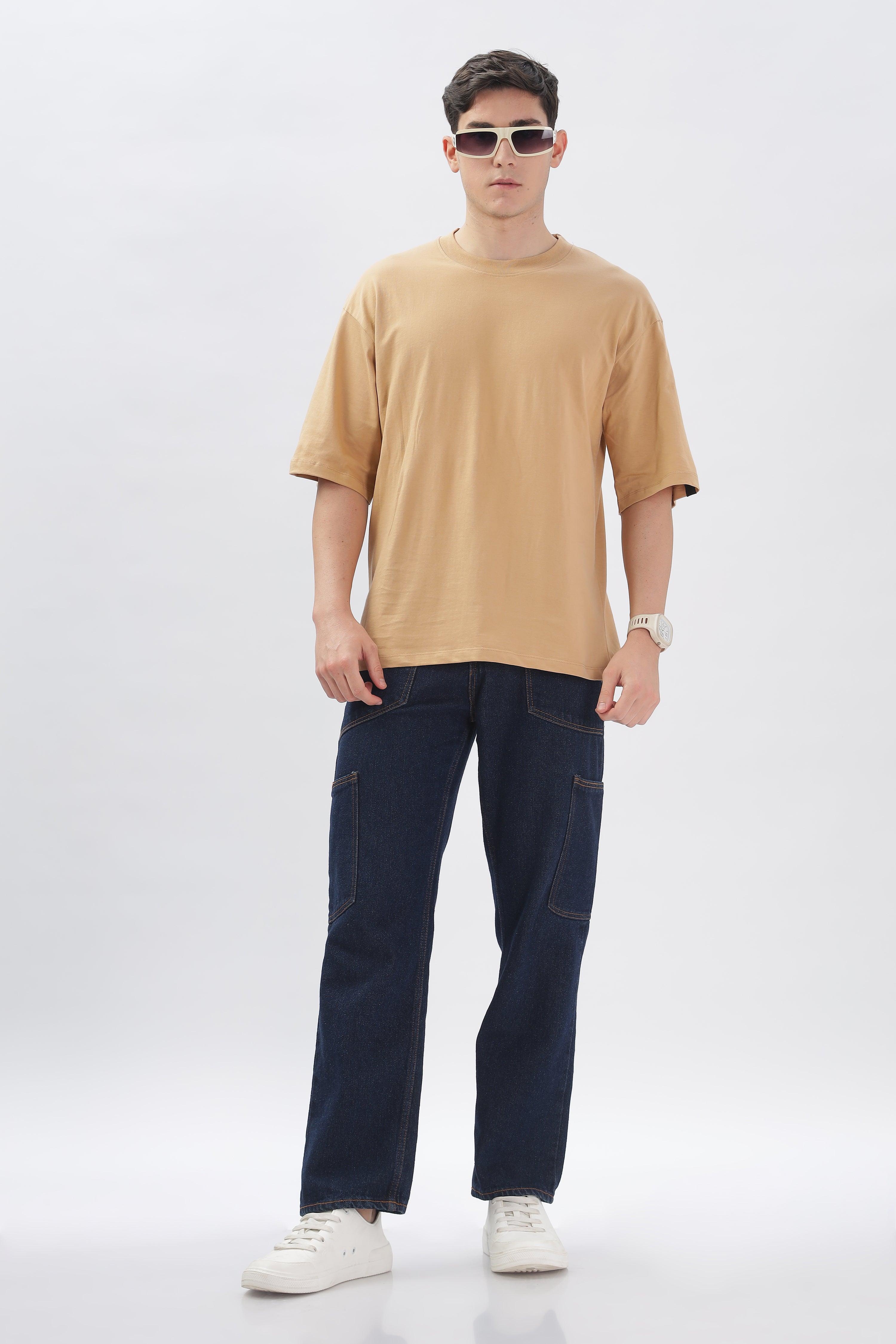 Male model wearing taupe oversized t-shirt paired with dark blue jeans and white sneakers