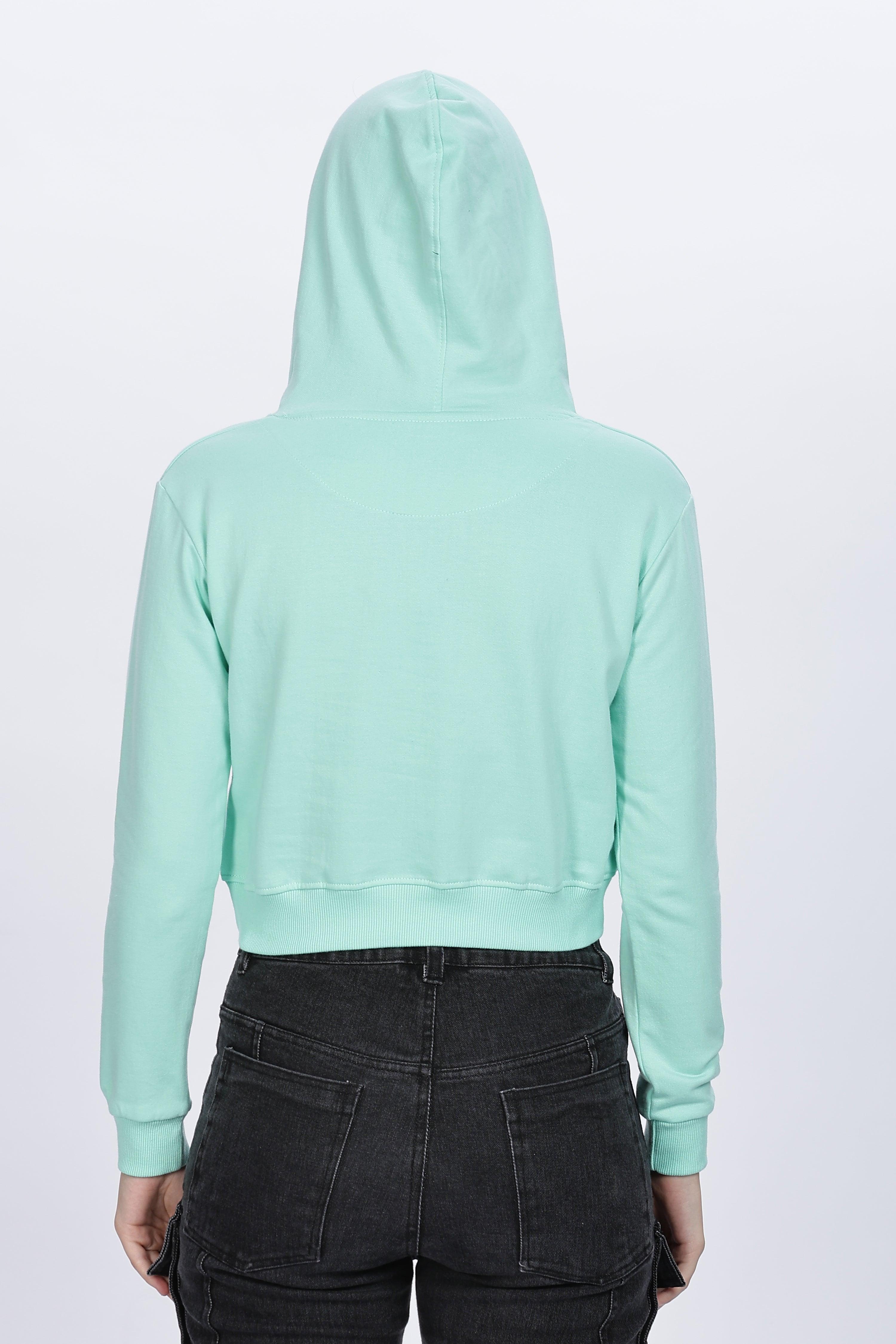 Back view of female wearing Soulmonk mint crop hoodie with hood up and black jeans