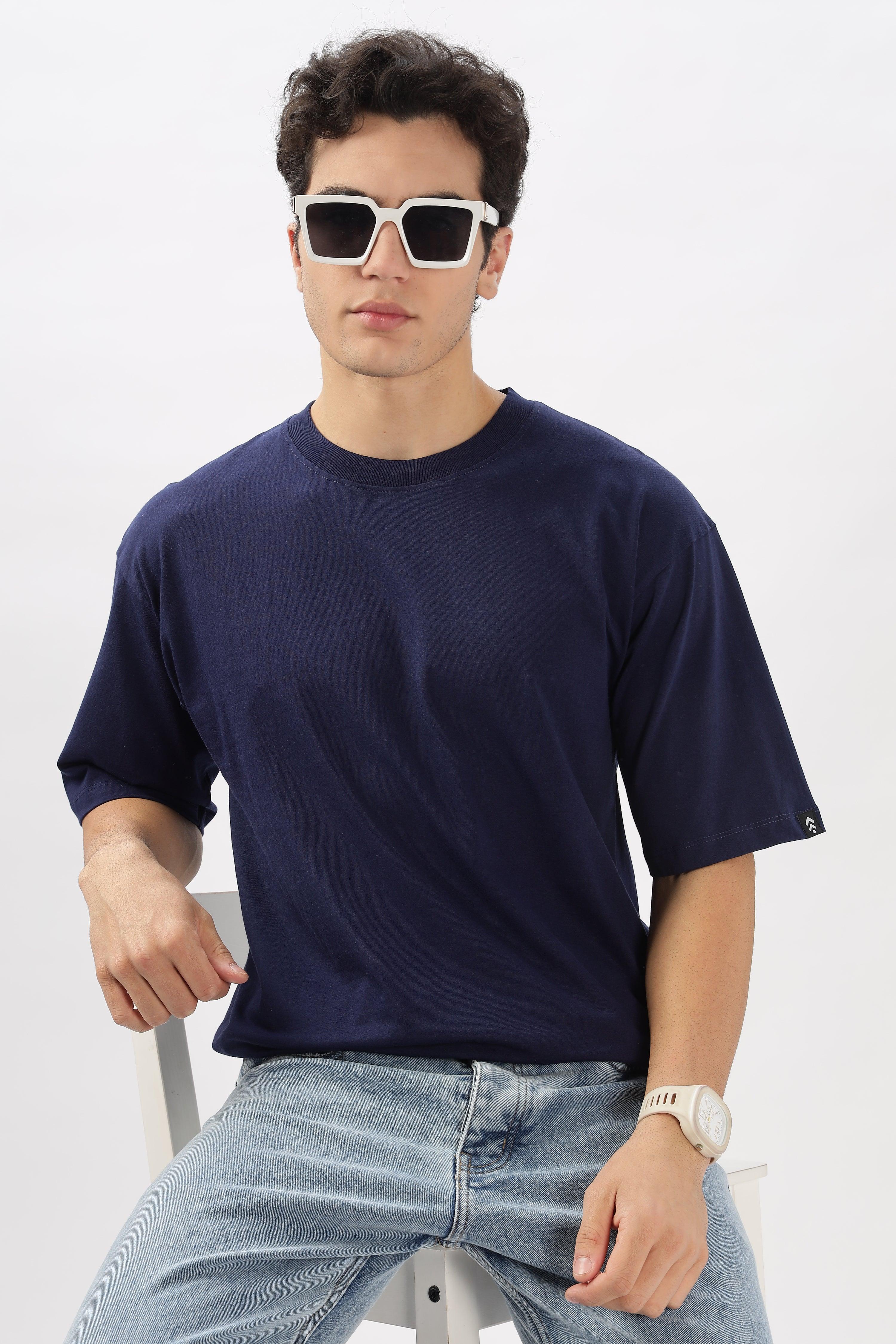 Male model wearing a navy blue oversized t-shirt by Soulmonk with light blue jeans and white sunglasses