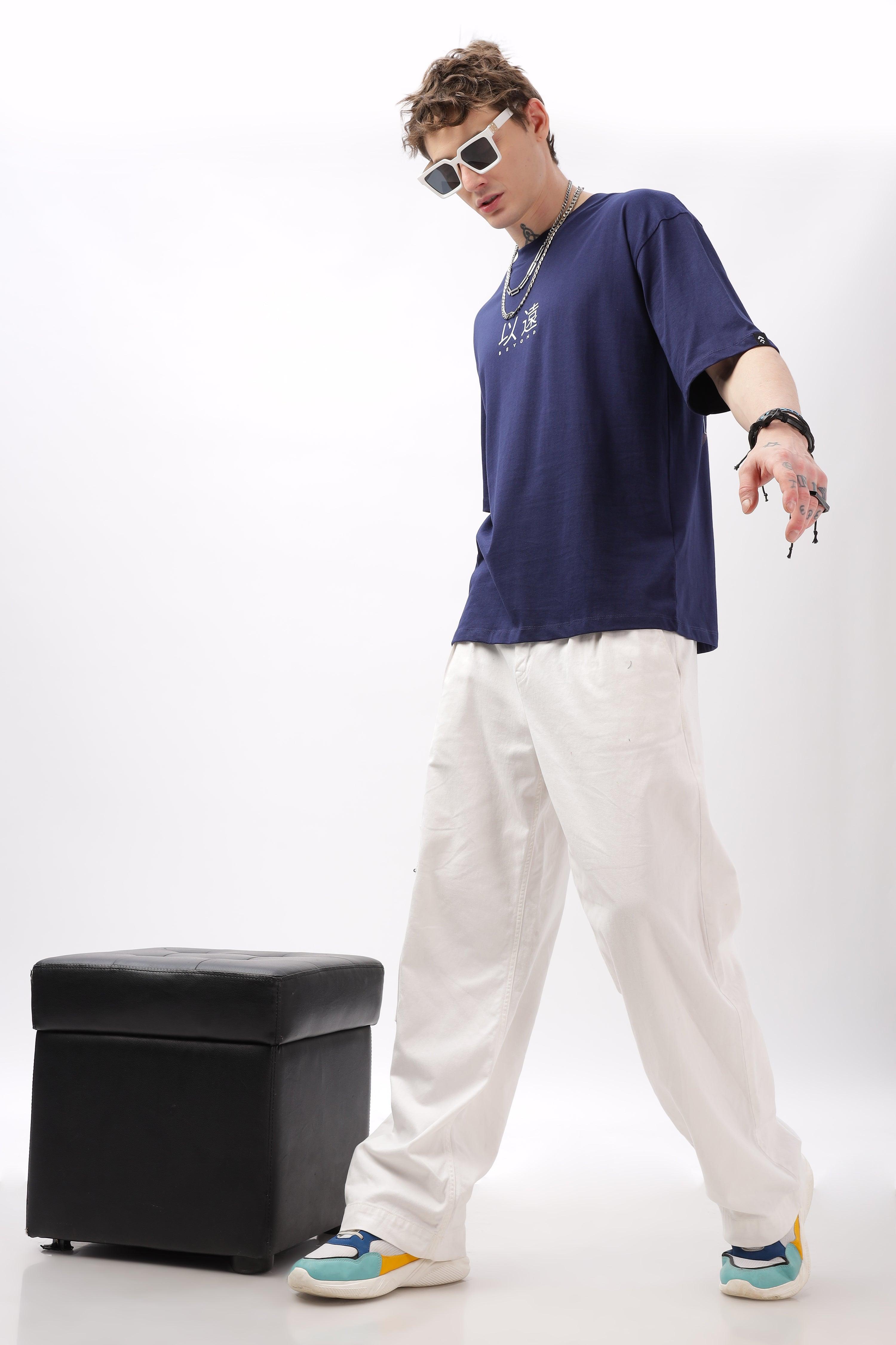 Male model wearing a navy blue oversized t-shirt by Soulmonk paired with white pants and colorful sneakers