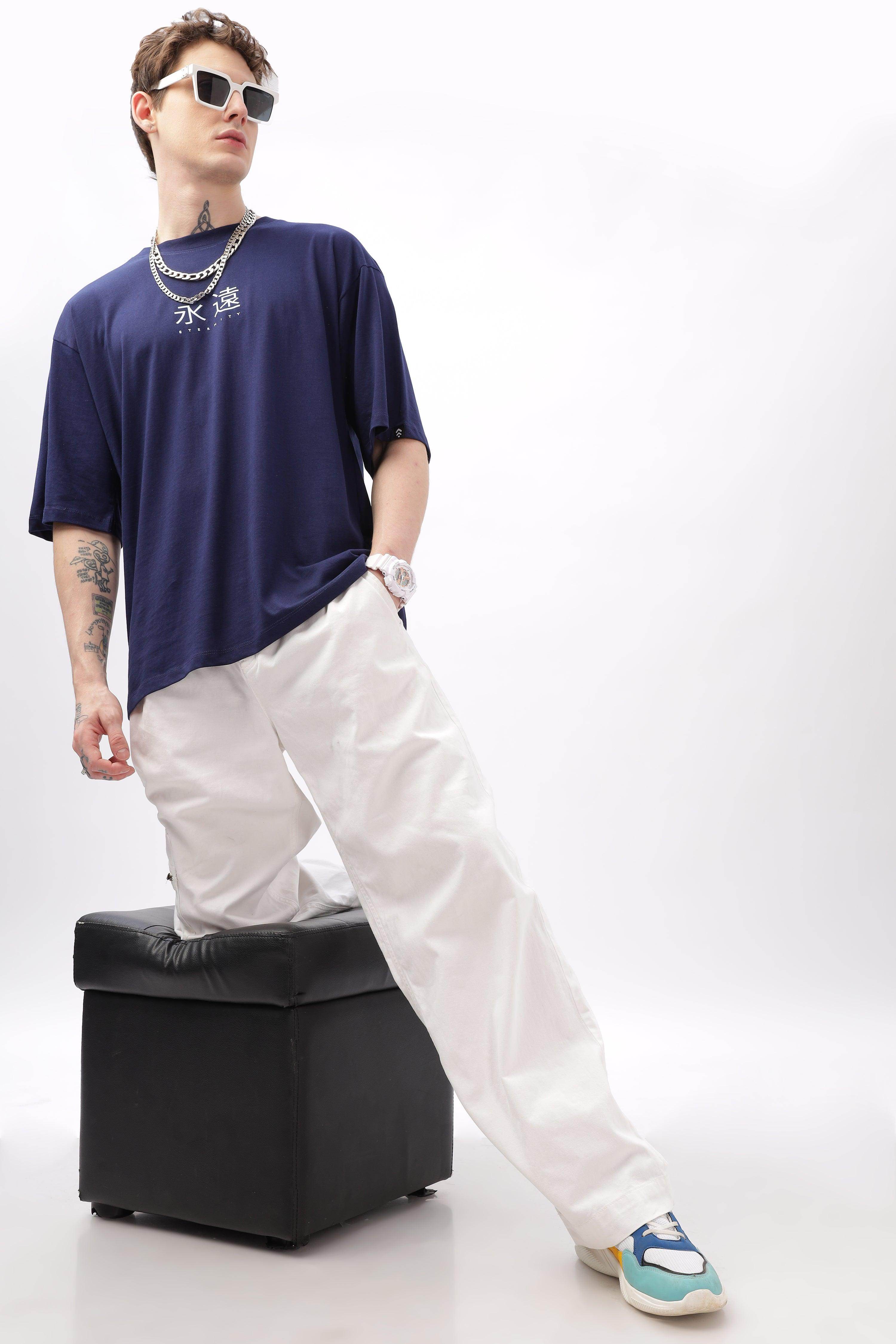Male model wearing navy blue oversized t-shirt from Soulmonk paired with white pants and sneakers
