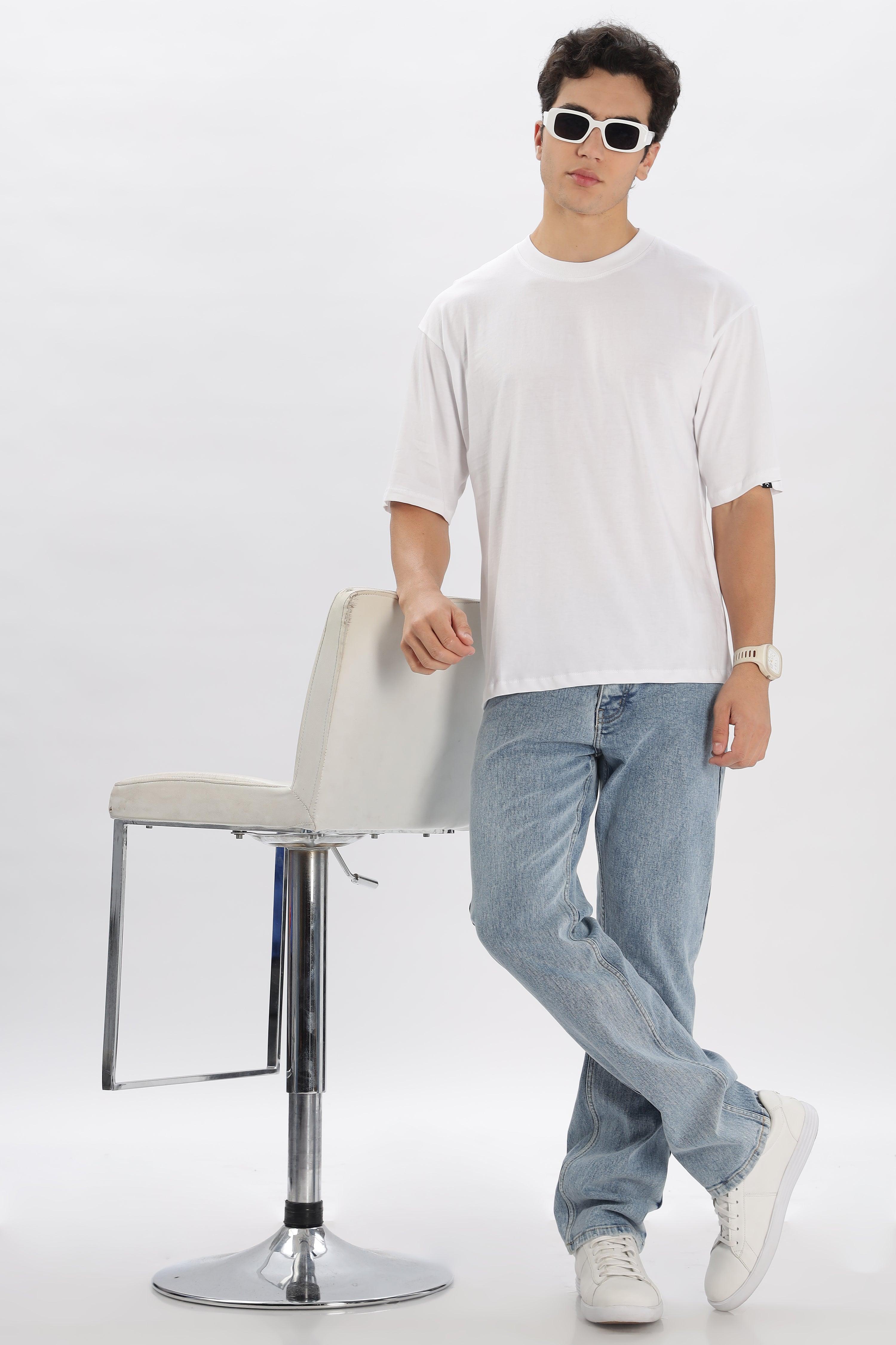 Male model wearing white oversized t-shirt for men paired with light blue jeans and white sneakers