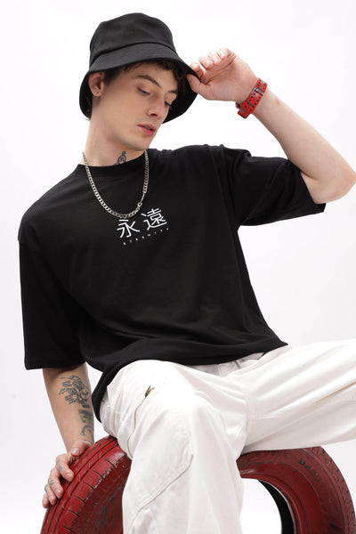 Black oversized t-shirt for men by Soulmonk with white graphic lettering worn with white pants and a black bucket hat
