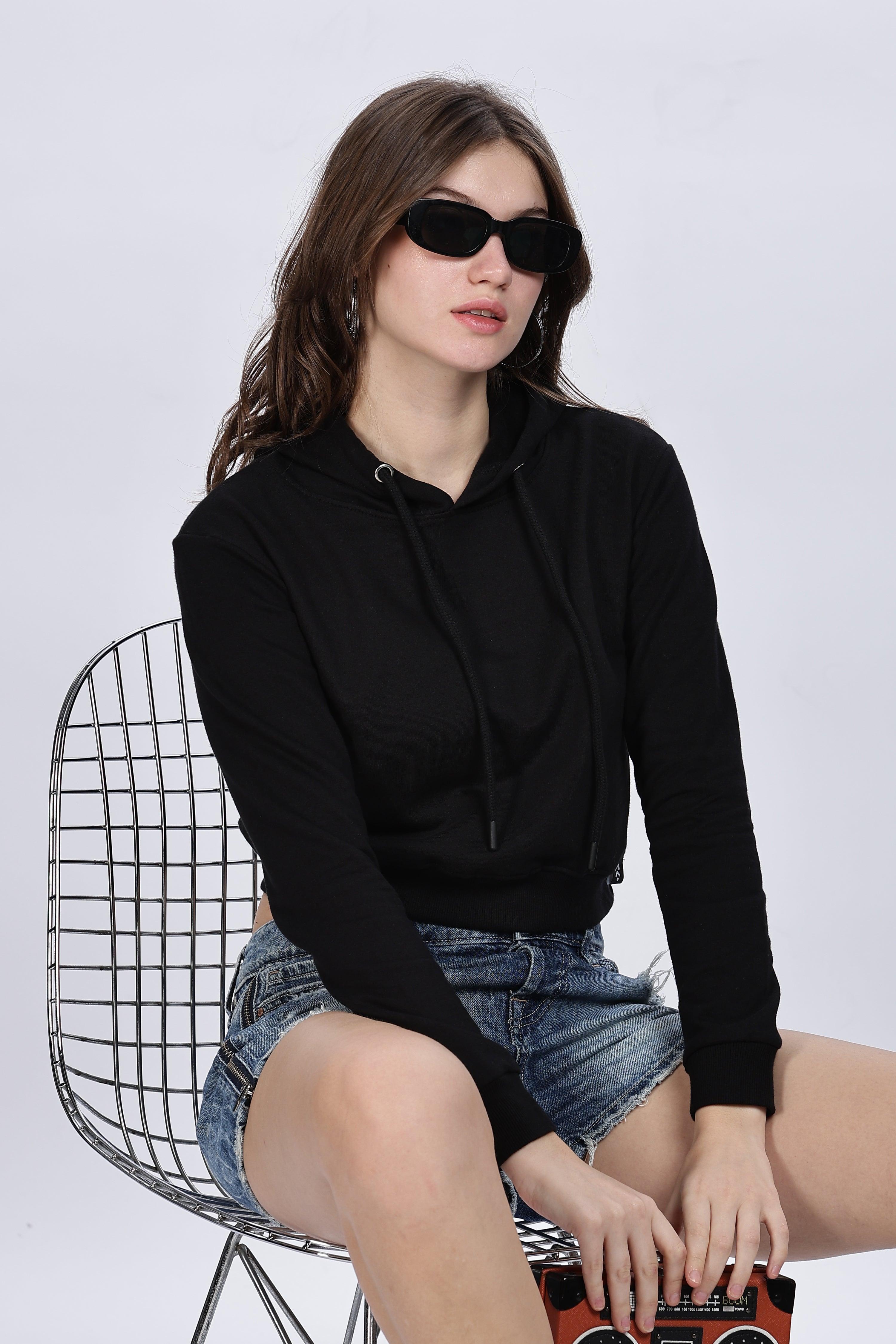 Soulmonk black crop hoodie for women worn with denim shorts and black sunglasses