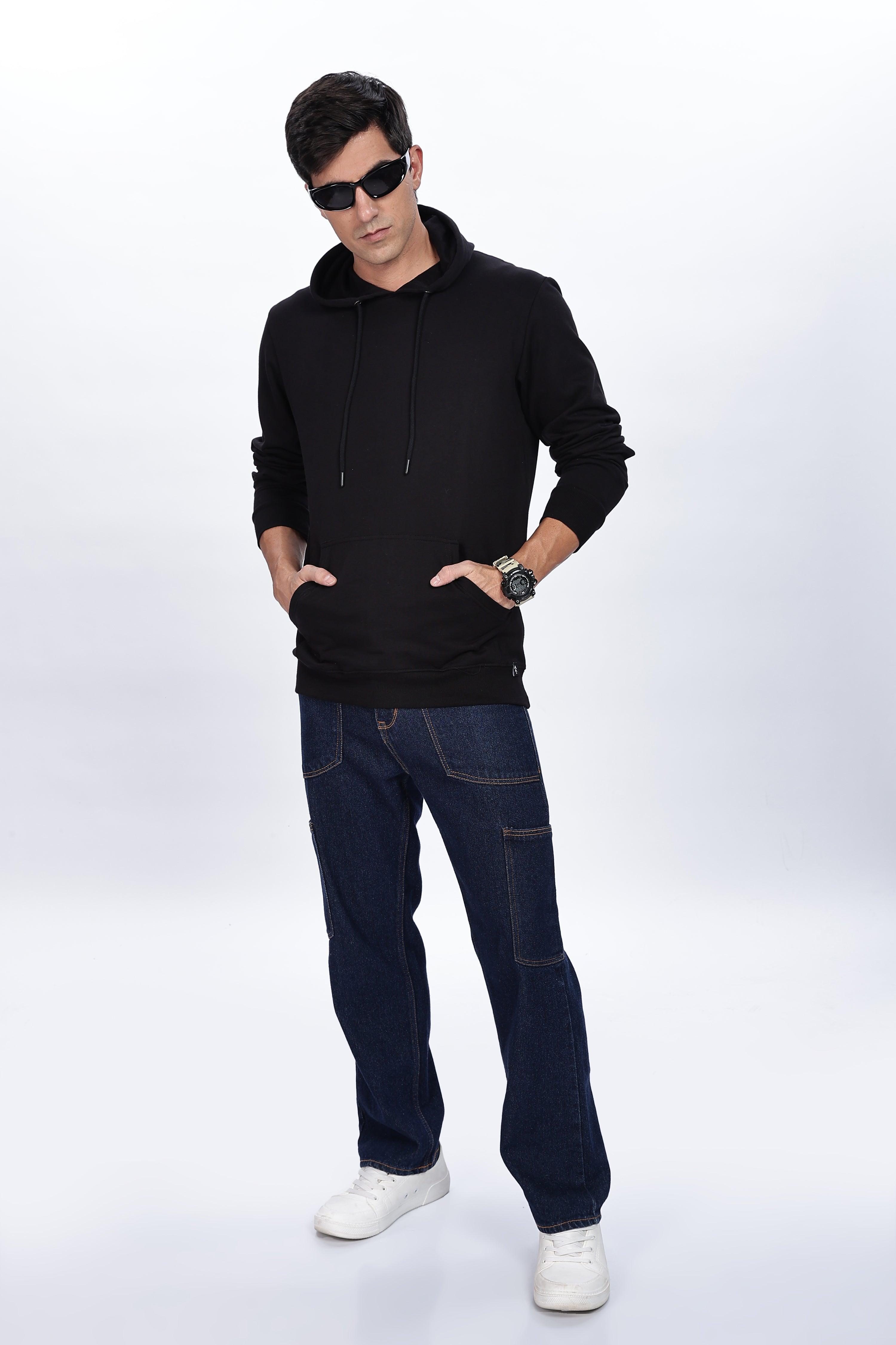 Male model wearing Soulmonk midnight black hoodie with front pockets and hood, paired with dark jeans and white sneakers