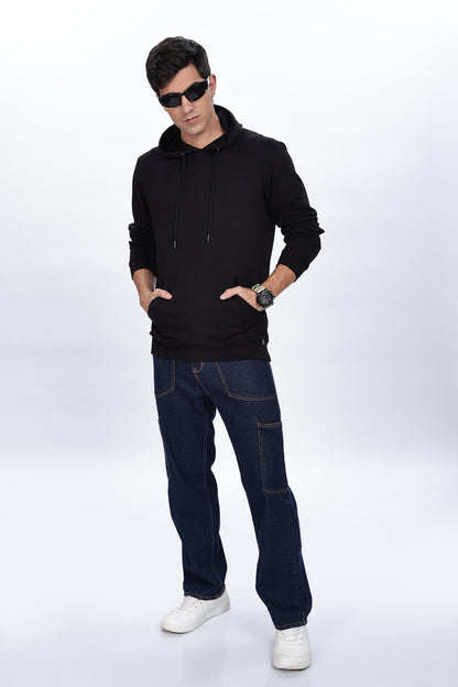 Male model wearing Soulmonk midnight black hoodie with front pockets and hood, paired with dark jeans and white sneakers