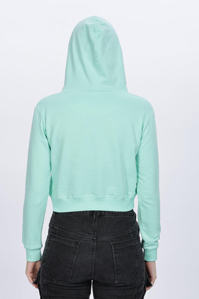 Back view of female wearing Soulmonk mint crop hoodie with hood up and black jeans