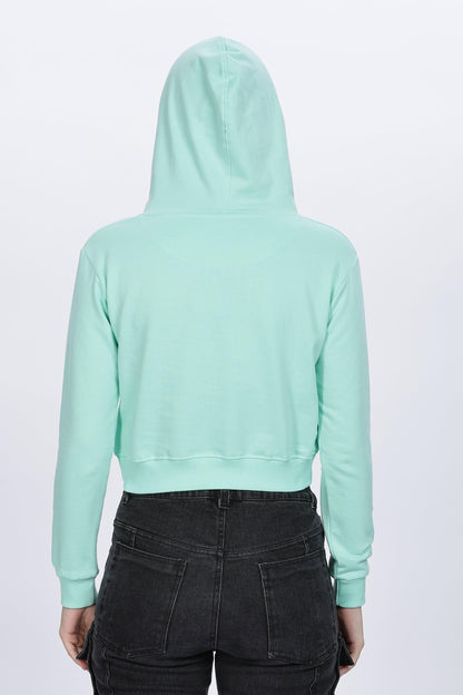 Back view of female wearing Soulmonk mint crop hoodie with hood up and black jeans