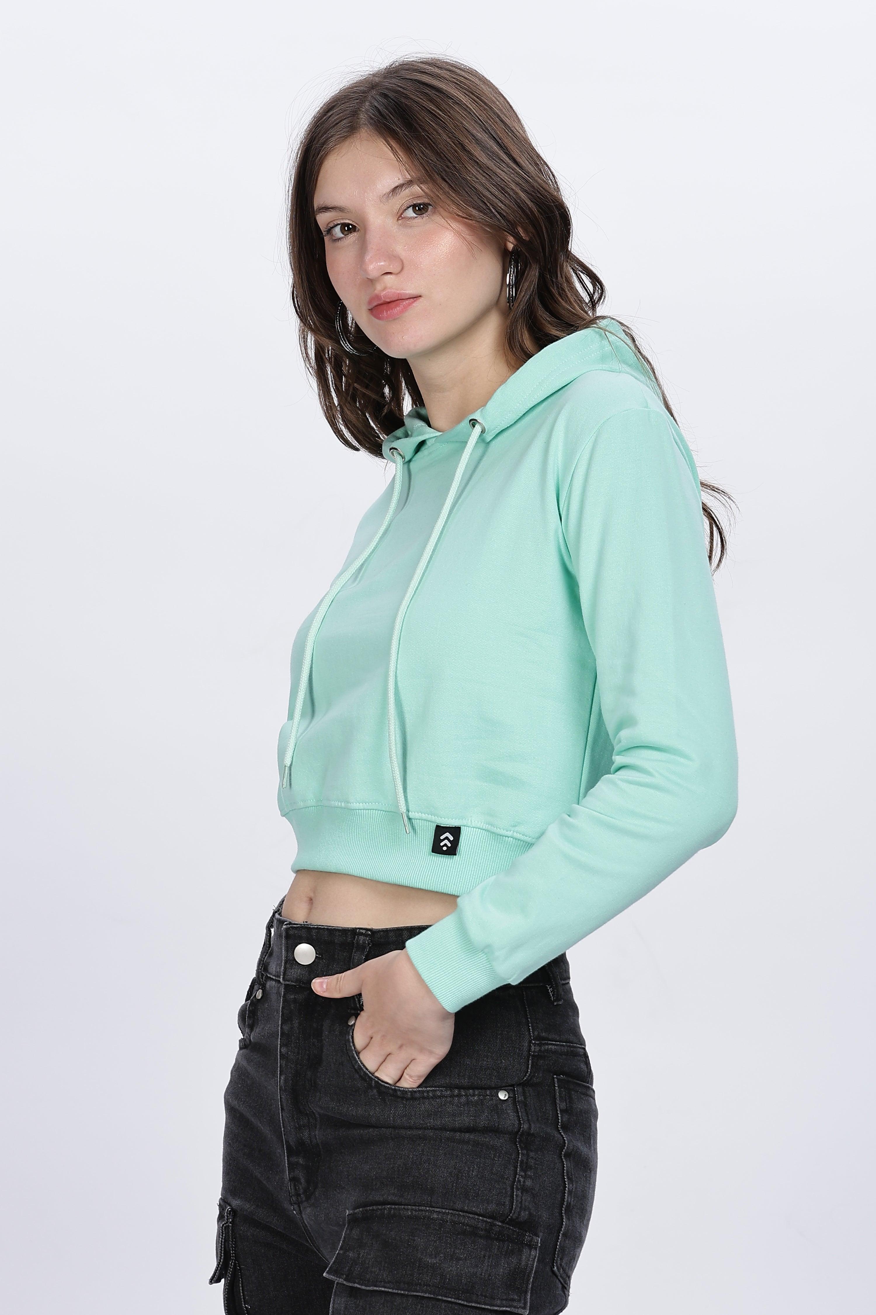 Soulmonk female model wearing a mint crop hoodie with long sleeves and drawstring hood