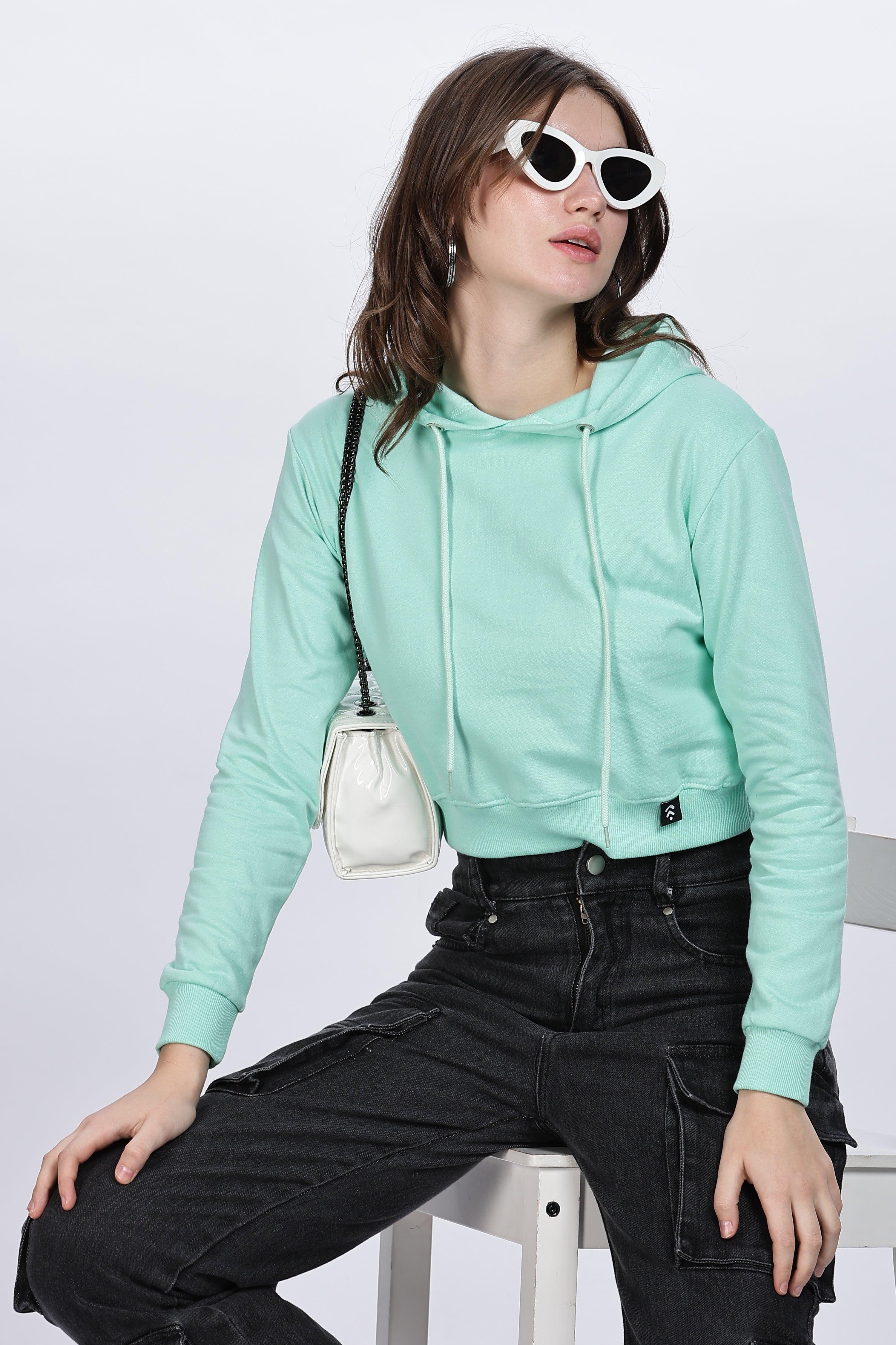 Soulmonk female model wearing a mint crop hoodie paired with black pants and white sunglasses