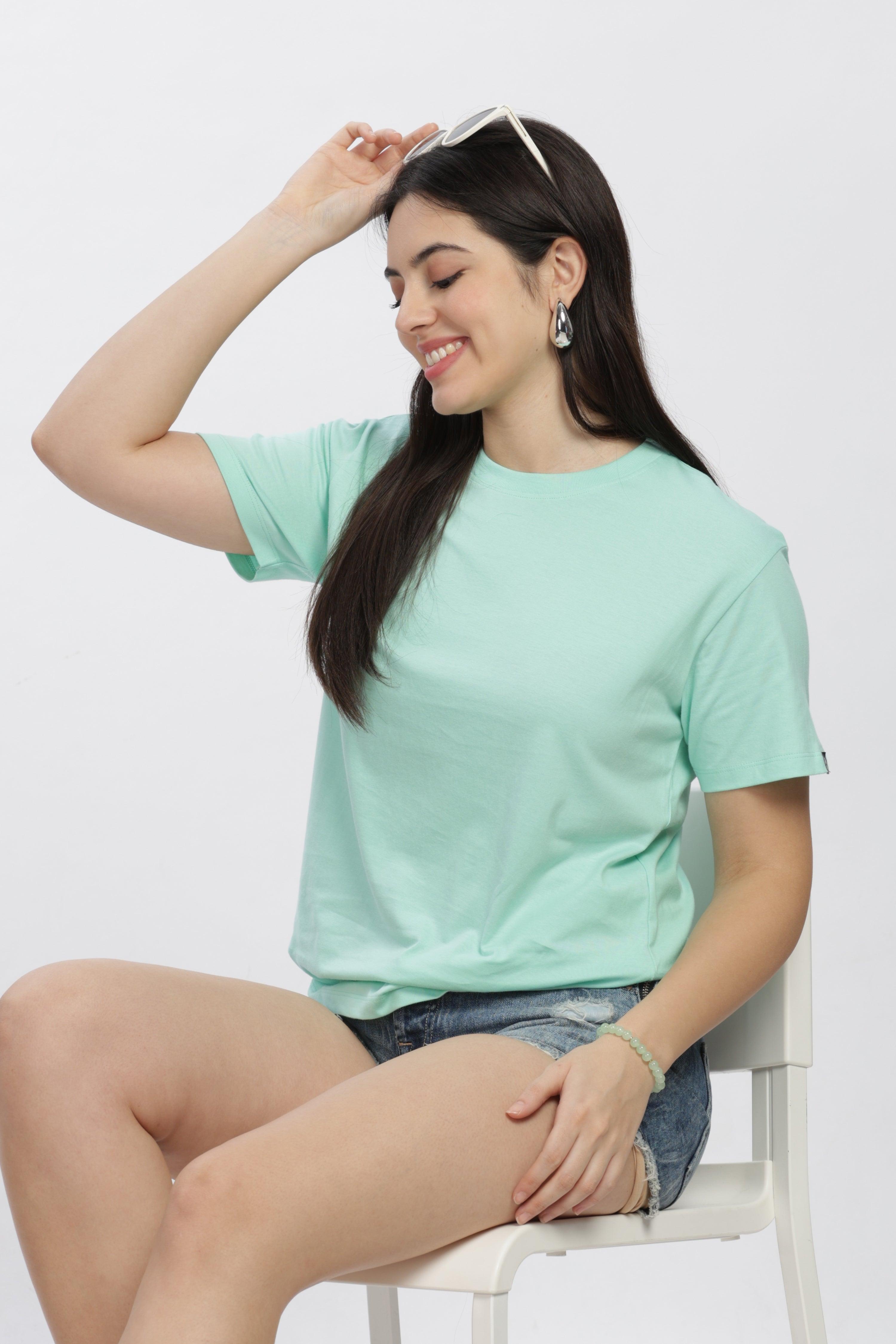 Soulmonk female model wearing a mint green casual t-shirt paired with denim shorts sitting on a white chair