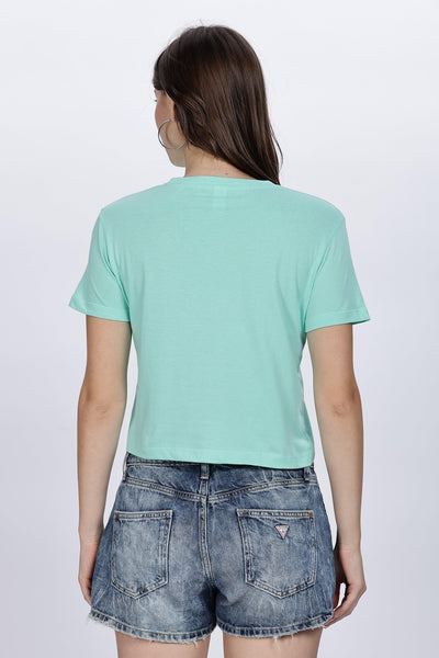 Back view of a woman wearing a mint green crop top for women paired with denim shorts