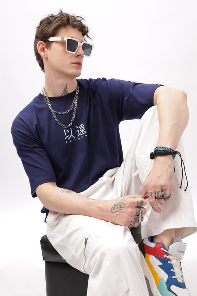 Male model wearing navy blue oversized t-shirt by Soulmonk paired with white pants and colorful sneakers