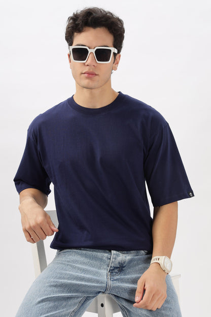 Male model wearing a navy blue oversized t-shirt by Soulmonk with light blue jeans and white sunglasses