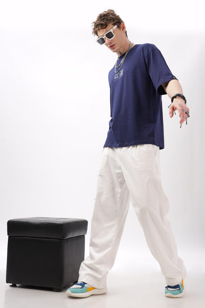 Male model wearing a navy blue oversized t-shirt by Soulmonk paired with white pants and colorful sneakers