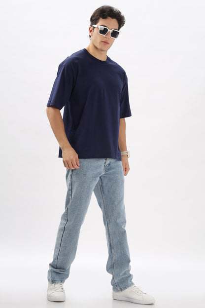 Male model wearing navy blue oversized t-shirt paired with light blue jeans and white sneakers