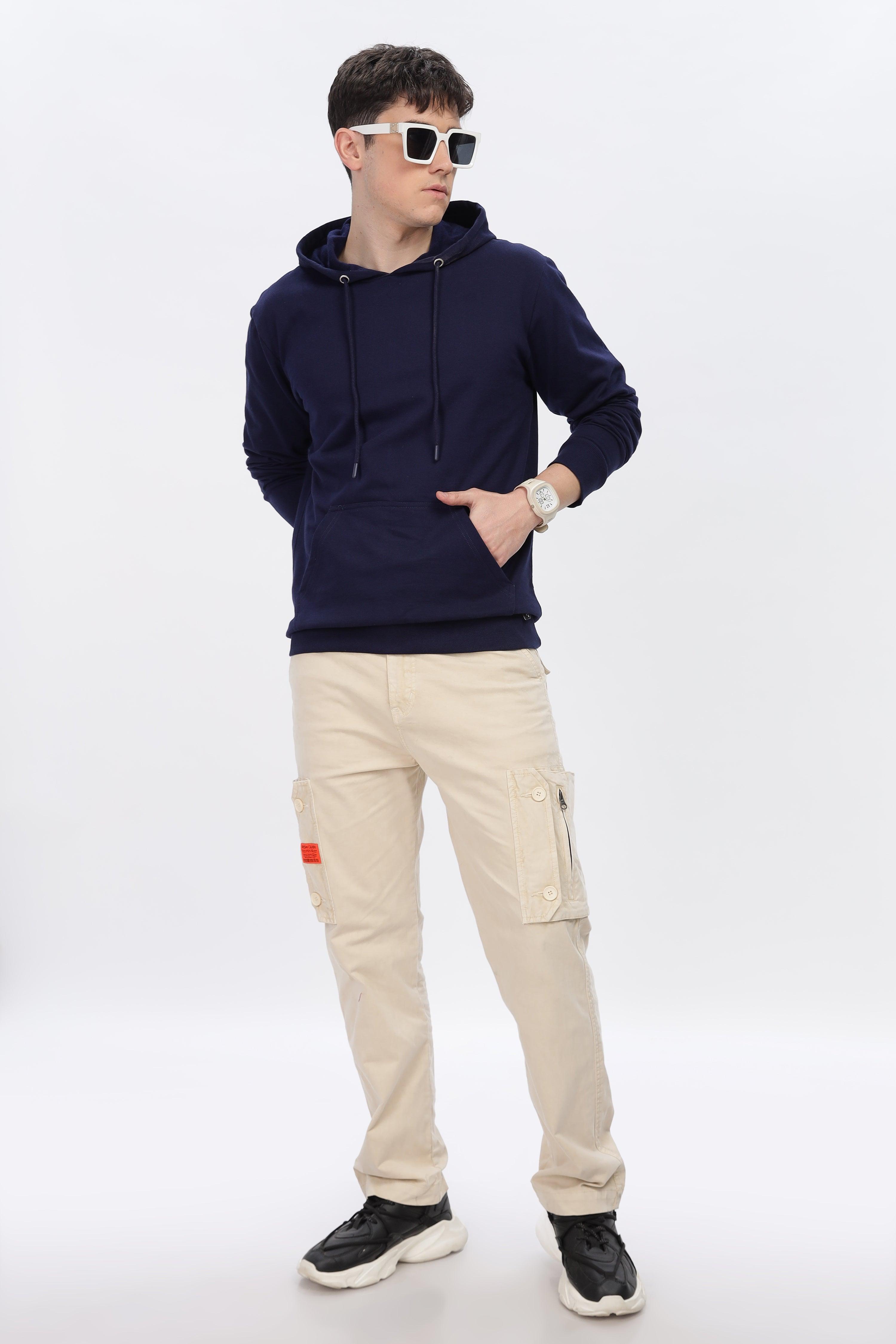 Male model wearing navy blue solid hoodie by Soulmonk with beige cargo pants and black sneakers