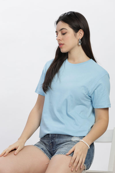Female model wearing SoulMonk ocean blue casual t-shirt paired with denim shorts sitting on white chair
