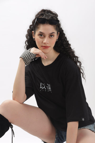 Soulmonk oversized black t-shirt for women with white graphic worn by a woman with curly hair and sunglasses