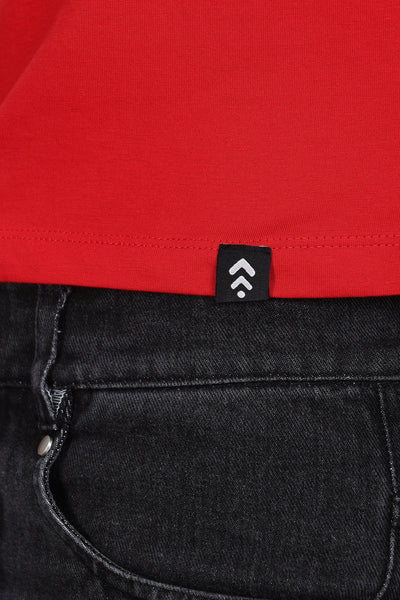 Close-up of Soulmonk red solid crop top hem with logo tag paired with black denim jeans