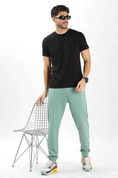 Soulmonk sage green joggers worn by man paired with black t-shirt and colorful sneakers