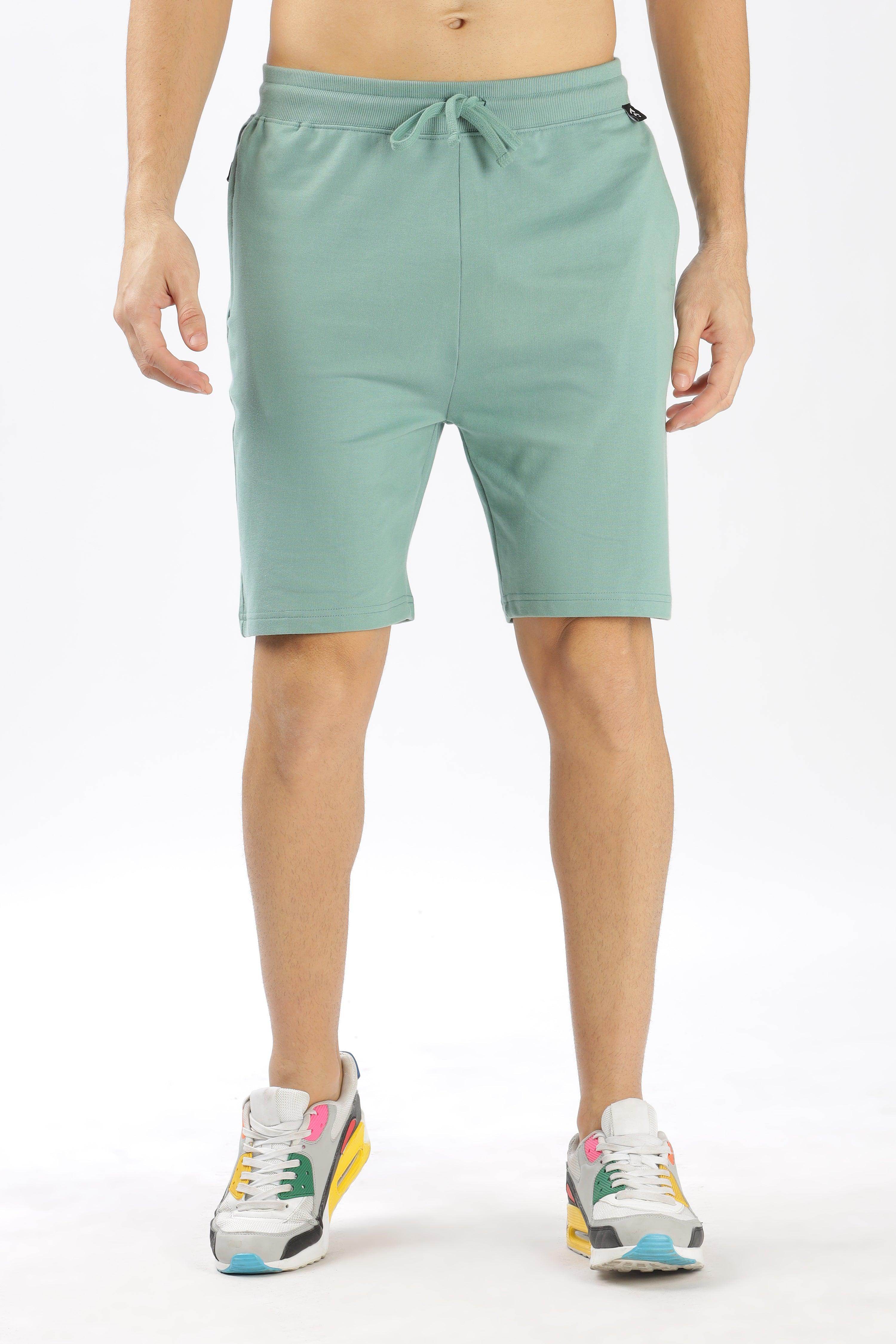 Soulmonk sage green shorts with drawstring waist worn by male model with sneakers