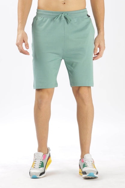 Soulmonk sage green shorts with drawstring waist worn by male model with sneakers