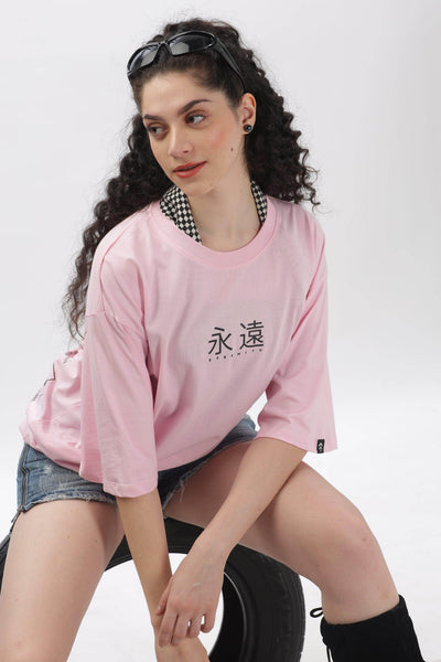 Soulmonk soft pink oversized t-shirt with black graphic print worn by woman with curly hair and denim shorts