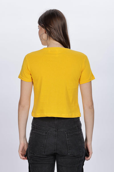 Female model wearing a soft yellow crop top from Soulmonk shown from the back with black pants