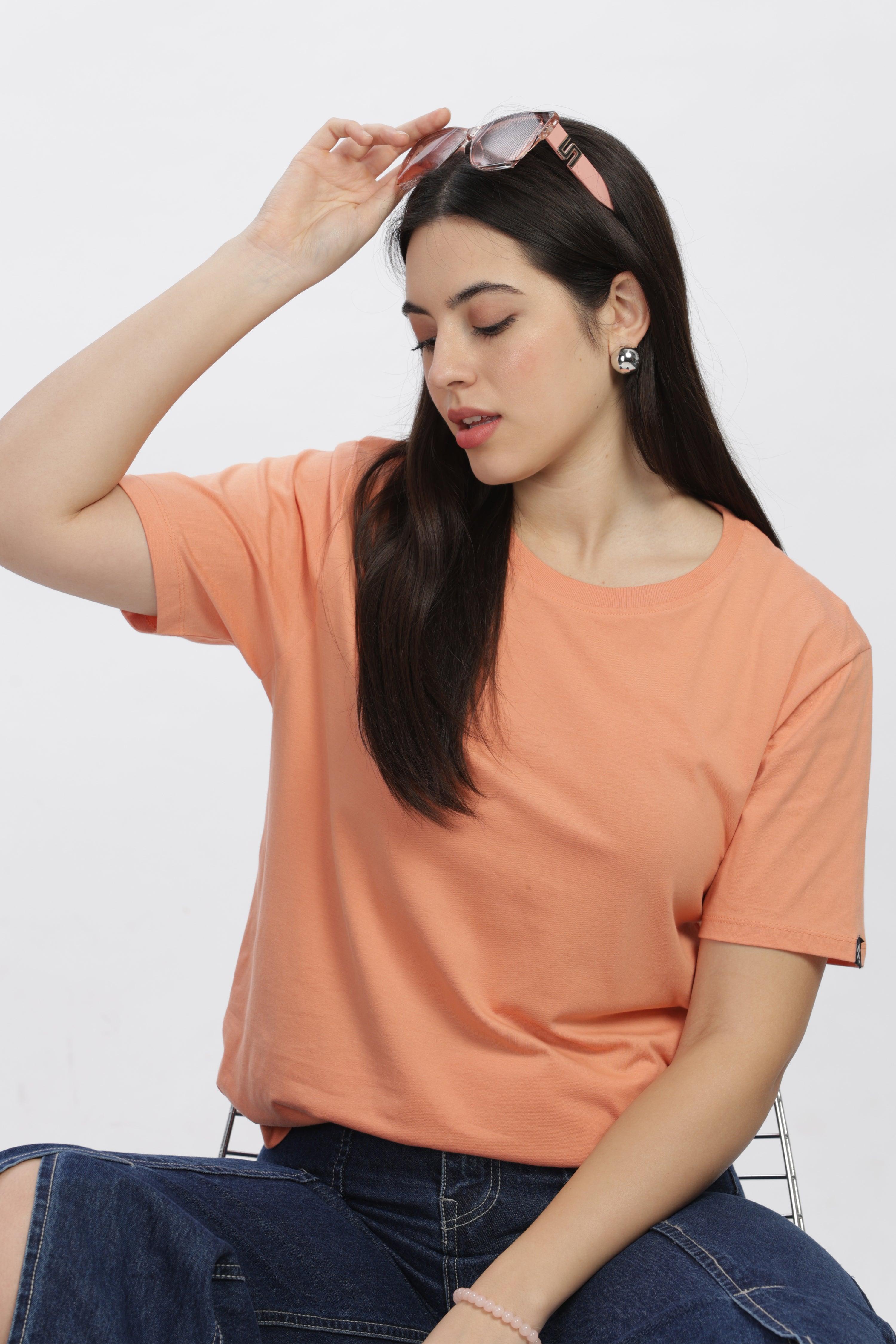 Soulmonk female model wearing a sunset relaxed fit t-shirt in soft orange paired with jeans