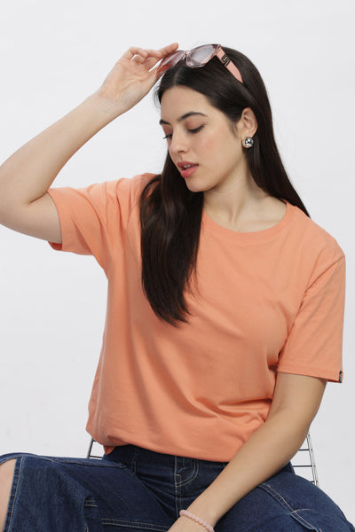 Soulmonk female model wearing a sunset relaxed fit t-shirt in soft orange paired with jeans