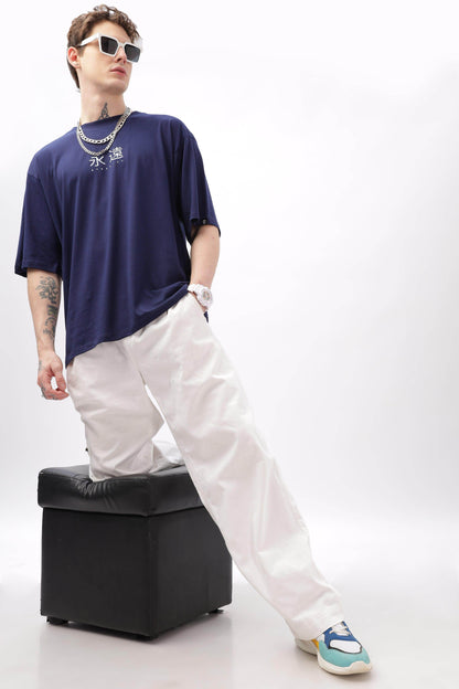 Male model wearing navy blue oversized t-shirt from Soulmonk paired with white pants and sneakers